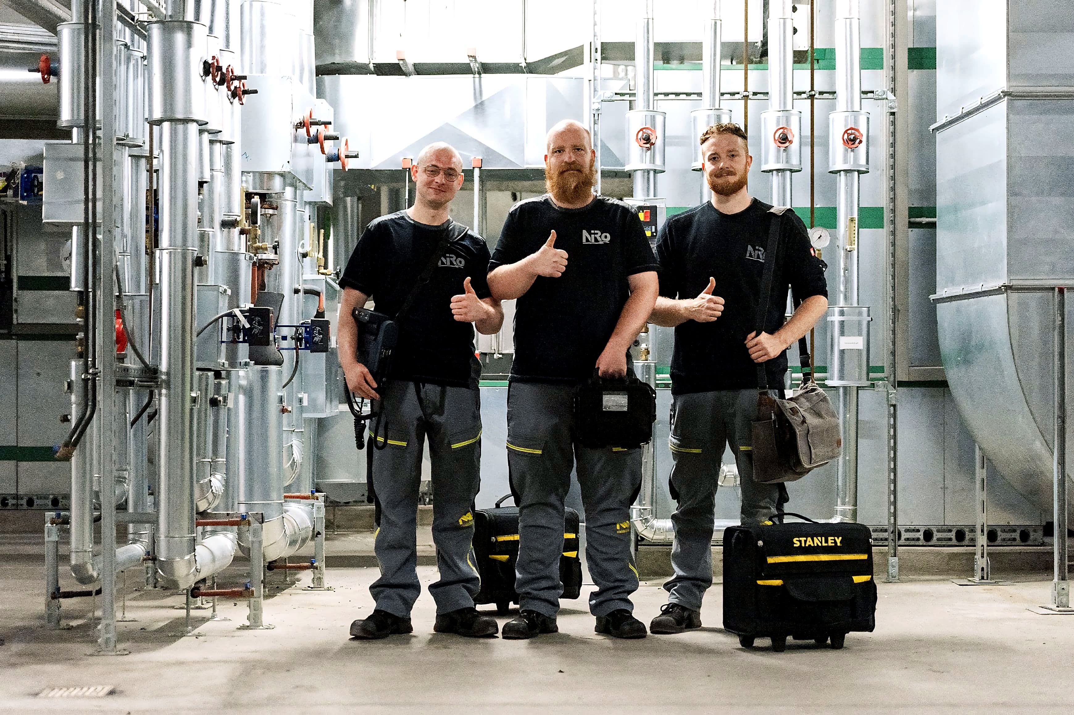 Drei NiRo-Mitarbeiter mit Prüfausrüstung in einer technischen Anlage